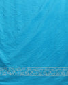 Sky blue Katan silk unstitched suit set block printed with tribal figures and circular mandalas in bright and light blue on the top piece, a dupatta bordered with linear geometric bands, and a plain bottom piece.